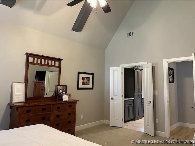 bedroom featuring ceiling fan, ensuite bathroom, high vaulted ceiling, and light carpet