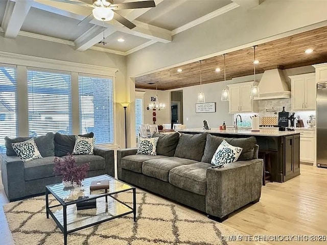 living room with beamed ceiling, ceiling fan with notable chandelier, light hardwood / wood-style floors, and ornamental molding