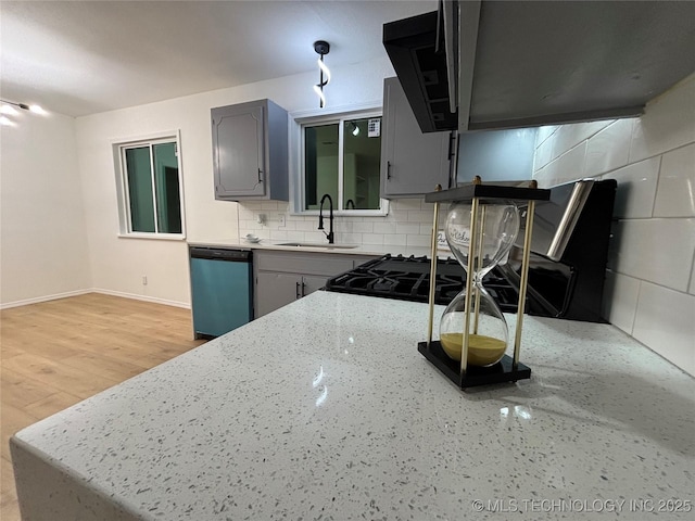 kitchen featuring tasteful backsplash, stainless steel dishwasher, sink, light wood-type flooring, and gray cabinetry