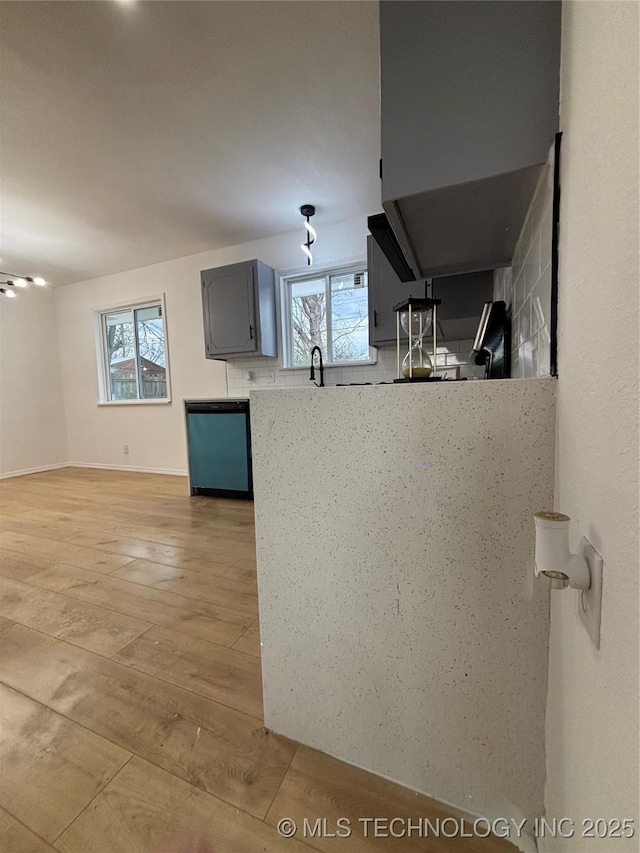 kitchen featuring light hardwood / wood-style floors, stainless steel dishwasher, plenty of natural light, and gray cabinets