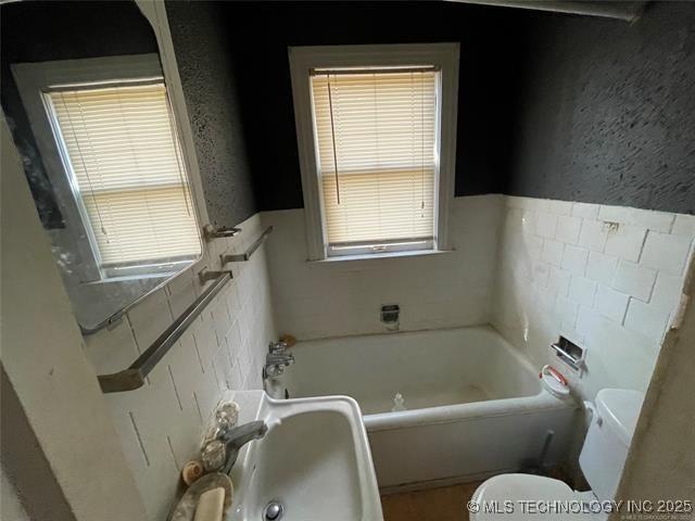 bathroom with a tub to relax in, sink, and a wealth of natural light