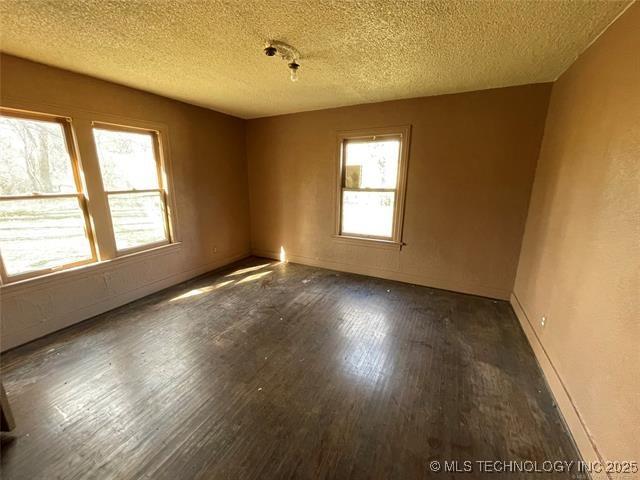 empty room with a textured ceiling and dark hardwood / wood-style flooring