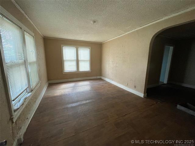 unfurnished room featuring a textured ceiling, plenty of natural light, and dark wood-type flooring