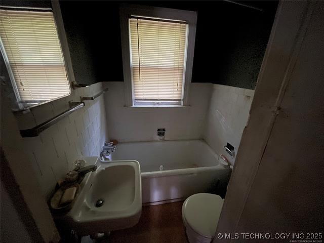 bathroom featuring a bathing tub, sink, and toilet