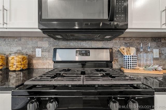 interior details with dark stone counters, decorative backsplash, gas stove, and white cabinets