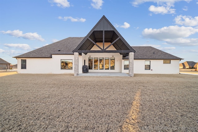 back of property with a patio and roof with shingles
