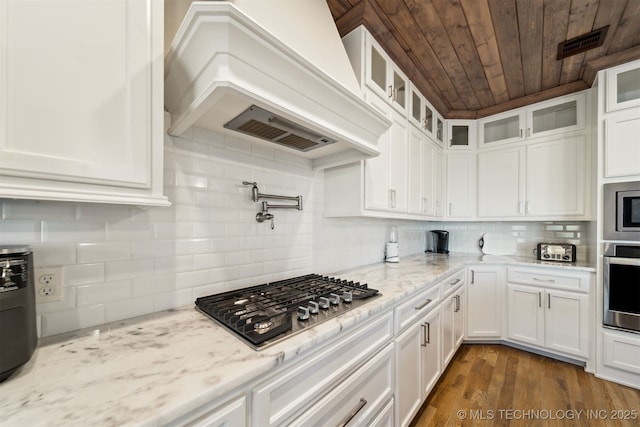 kitchen featuring white cabinetry, light stone counters, custom exhaust hood, wood ceiling, and appliances with stainless steel finishes