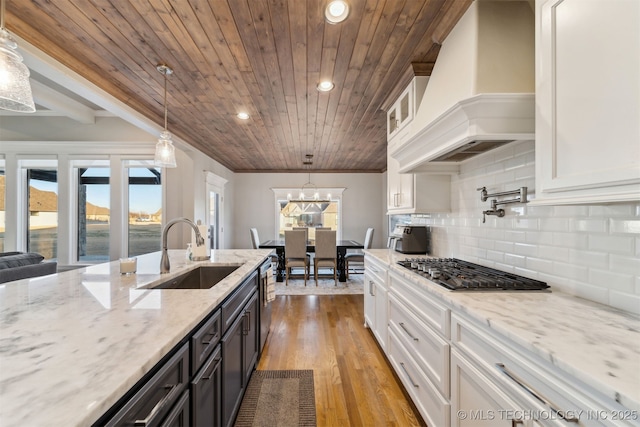 kitchen with custom exhaust hood, decorative light fixtures, white cabinetry, wooden ceiling, and sink