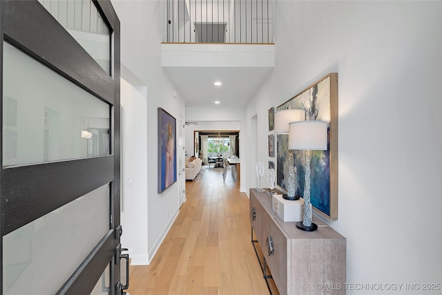 hallway with light hardwood / wood-style flooring and a high ceiling