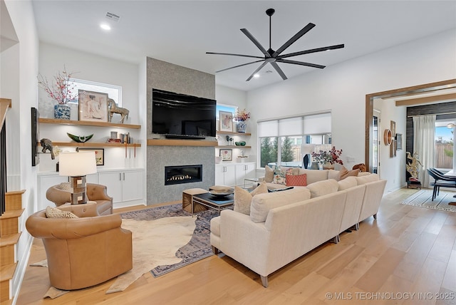 living room with light hardwood / wood-style floors, ceiling fan, and a fireplace