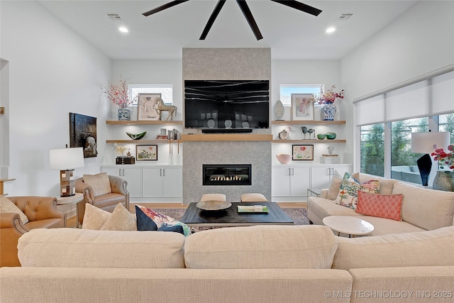 living room with a fireplace, wood-type flooring, and ceiling fan