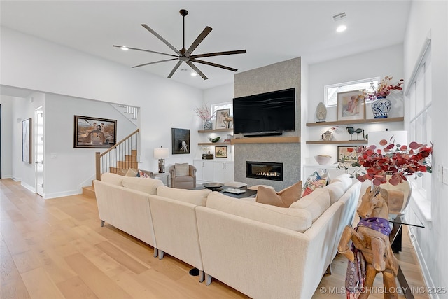 living room featuring a fireplace, light hardwood / wood-style flooring, and ceiling fan