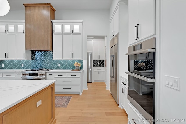 kitchen with white cabinets, high end appliances, and light stone counters