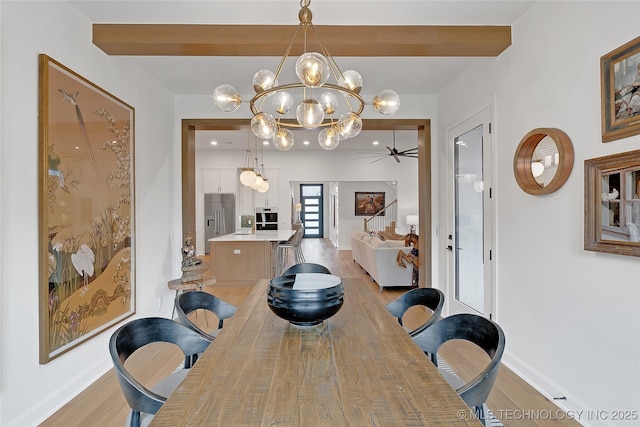 dining space with light wood-type flooring, ceiling fan with notable chandelier, and beam ceiling