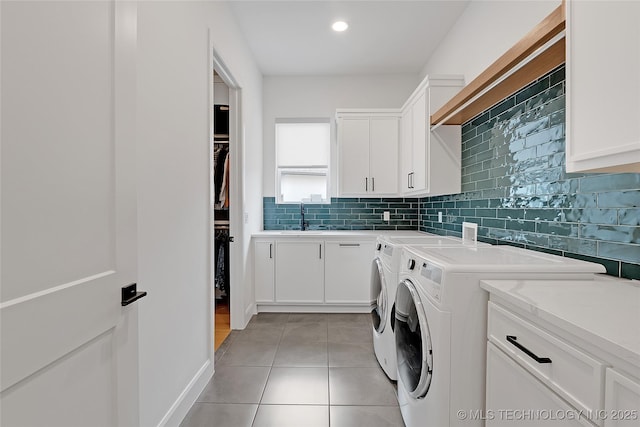 clothes washing area with sink, cabinets, light tile patterned floors, and washing machine and clothes dryer