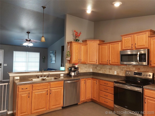 kitchen featuring lofted ceiling, sink, appliances with stainless steel finishes, tasteful backsplash, and kitchen peninsula