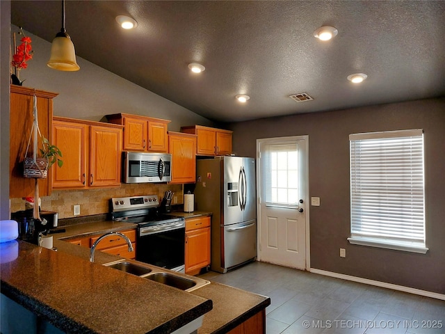 kitchen featuring kitchen peninsula, tasteful backsplash, stainless steel appliances, vaulted ceiling, and decorative light fixtures