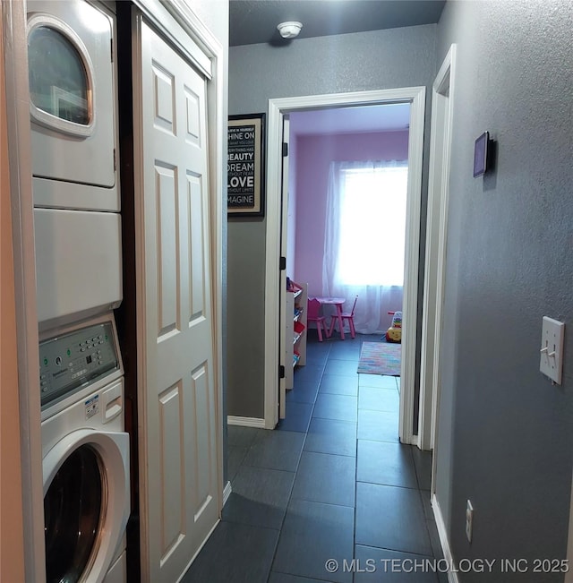 washroom with dark tile patterned flooring and stacked washer and clothes dryer