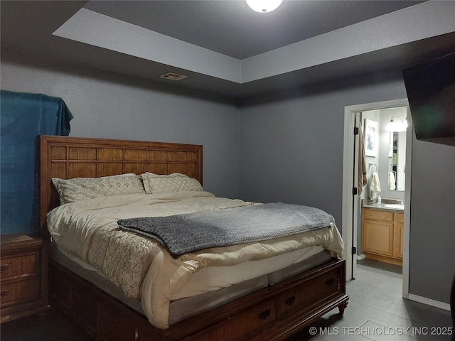 bedroom featuring ensuite bathroom and a tray ceiling