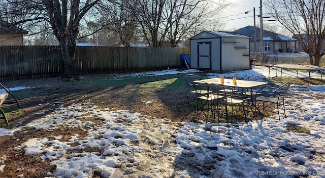 yard layered in snow with a shed and a trampoline