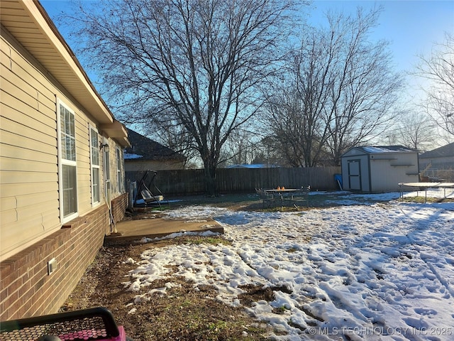 yard covered in snow with a storage unit and a trampoline