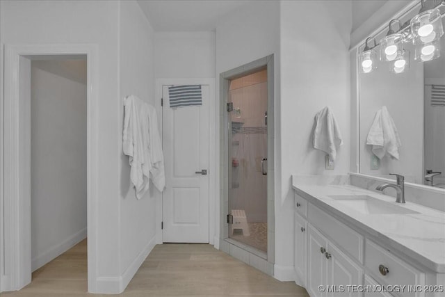 bathroom with hardwood / wood-style flooring, walk in shower, and vanity