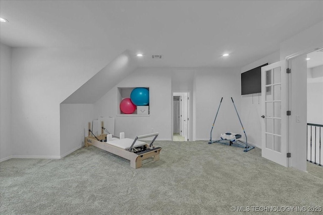 exercise room with lofted ceiling and light colored carpet