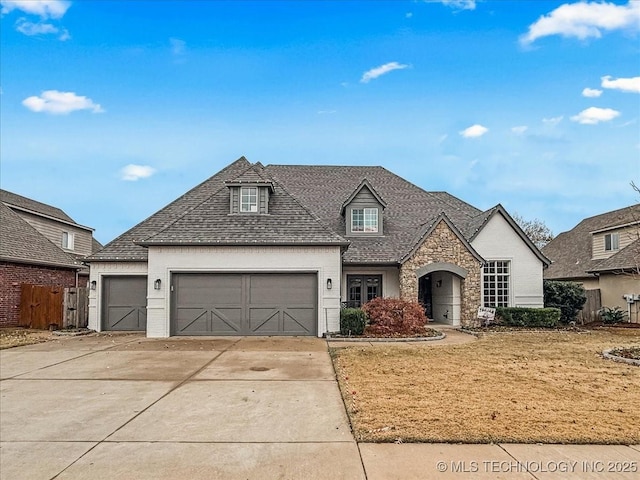 french provincial home with a front lawn and a garage