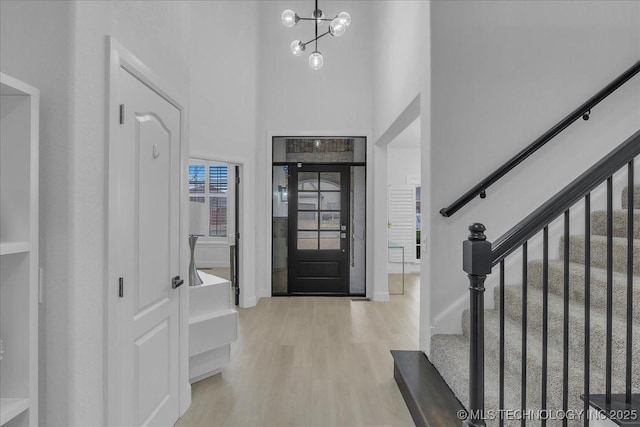 entryway featuring a high ceiling, an inviting chandelier, and light hardwood / wood-style floors