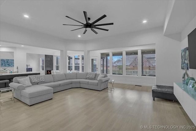 living room featuring sink, ceiling fan, and light hardwood / wood-style flooring