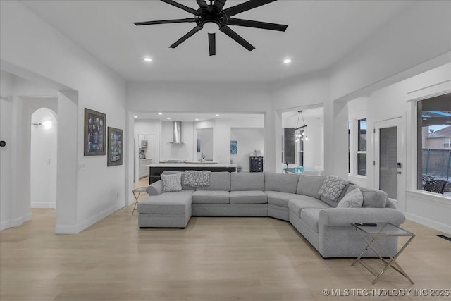 living room featuring light wood-type flooring and ceiling fan with notable chandelier