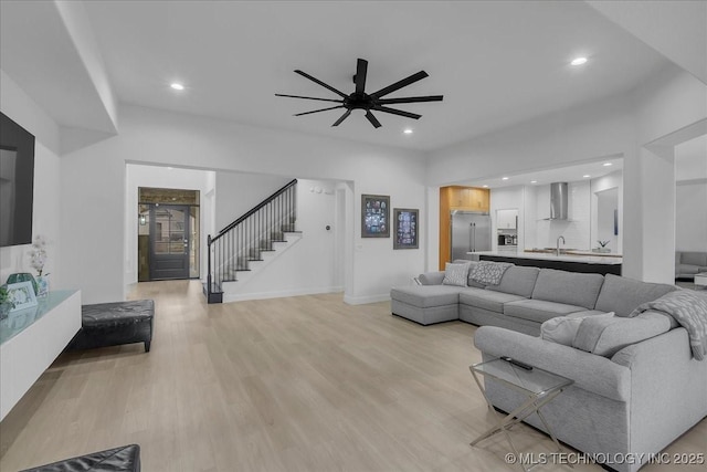 living room featuring light hardwood / wood-style floors, ceiling fan, and sink