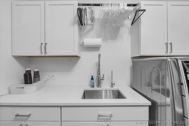 kitchen featuring washer / dryer, white cabinets, sink, and light stone countertops