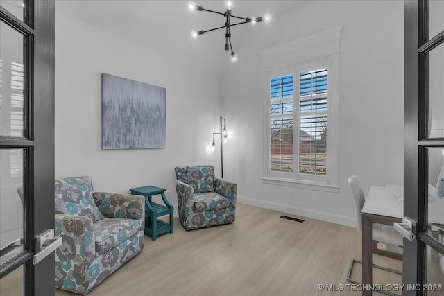 sitting room with an inviting chandelier and light hardwood / wood-style flooring