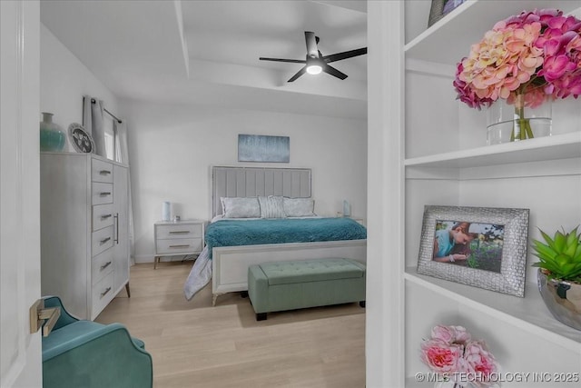 bedroom with ceiling fan, light hardwood / wood-style floors, and a tray ceiling