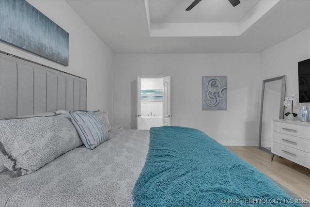 bedroom with a raised ceiling, ceiling fan, and light wood-type flooring