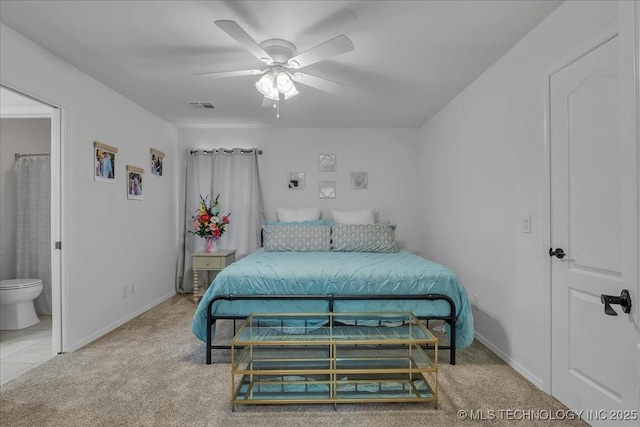 carpeted bedroom with ensuite bath and ceiling fan