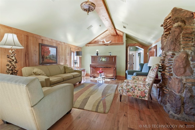 living room with vaulted ceiling with beams, wooden walls, and hardwood / wood-style floors