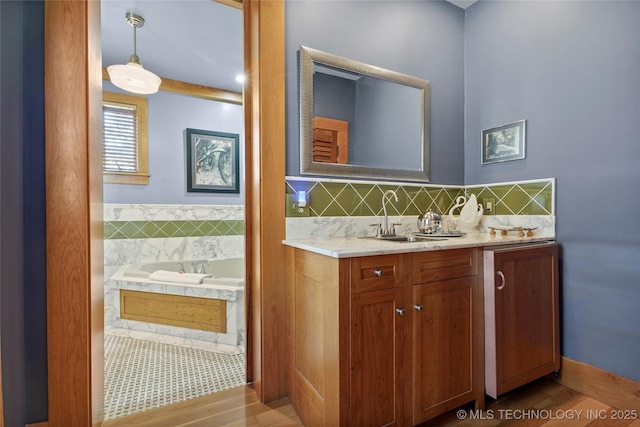 bathroom featuring hardwood / wood-style floors, vanity, a tub, and tasteful backsplash