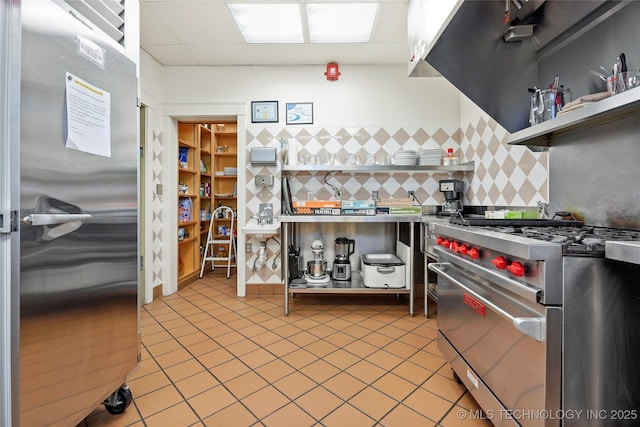 kitchen with decorative backsplash, a drop ceiling, light tile patterned floors, and appliances with stainless steel finishes