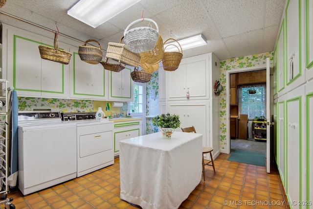 kitchen with a drop ceiling, white cabinetry, and independent washer and dryer