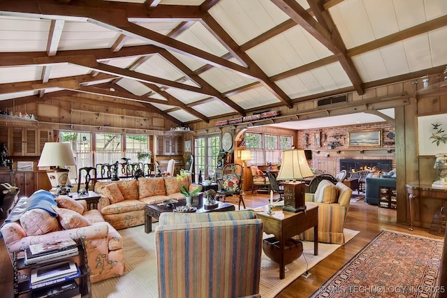 living room featuring wood walls, beamed ceiling, and a healthy amount of sunlight