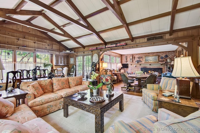 living room featuring a fireplace, beamed ceiling, high vaulted ceiling, and wooden walls