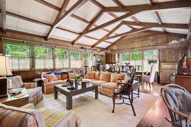 living room featuring wood walls, light hardwood / wood-style floors, beam ceiling, and high vaulted ceiling