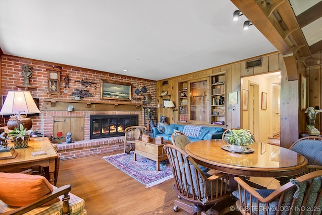 dining space with wood walls, light hardwood / wood-style floors, built in features, and a fireplace