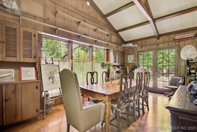 dining area with vaulted ceiling with beams, wood walls, french doors, and a healthy amount of sunlight