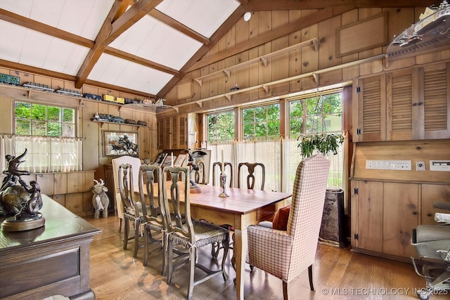 dining space with vaulted ceiling with beams, wood walls, and light wood-type flooring