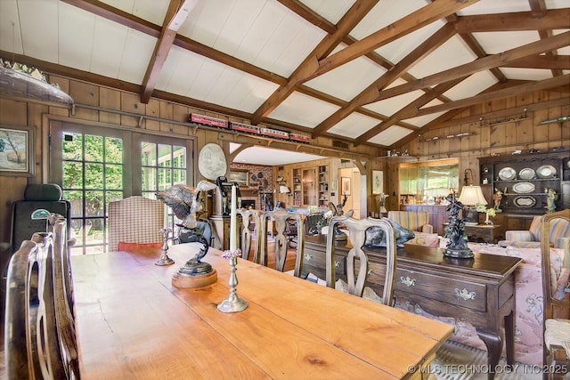 dining space featuring vaulted ceiling with beams and wood walls