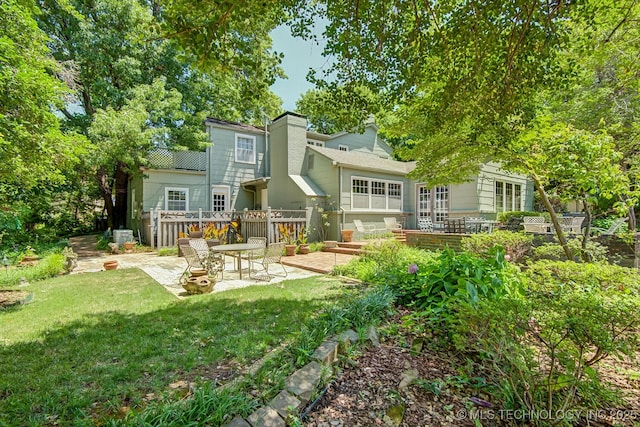 rear view of house with a lawn and a patio