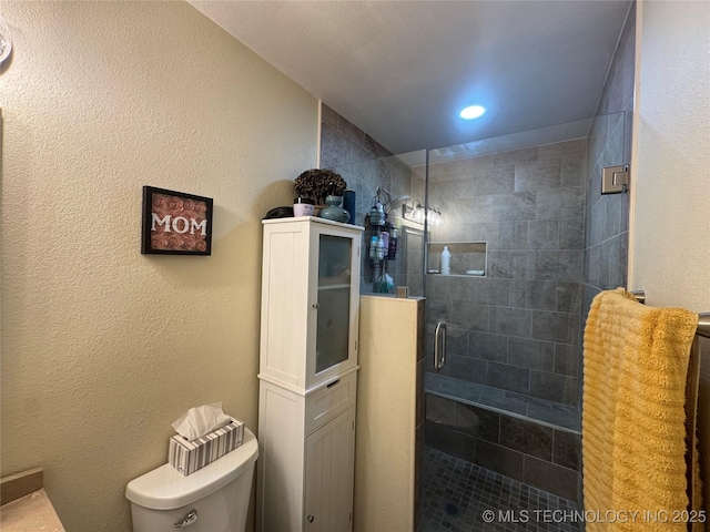 bathroom featuring toilet and a shower with door